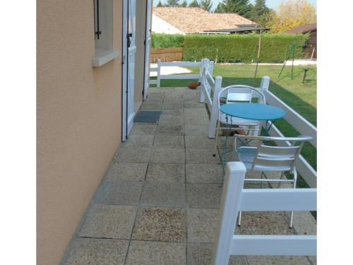 un patio con sillas blancas y una mesa azul en les Eglantines en Casteljaloux