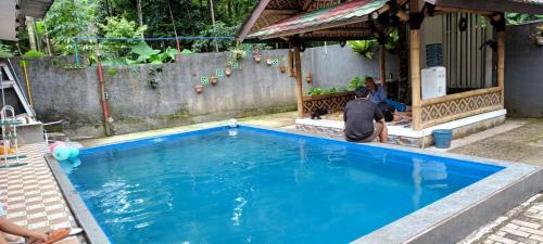 a man sitting next to a blue swimming pool at Villa Roemah JPS New in Bogor