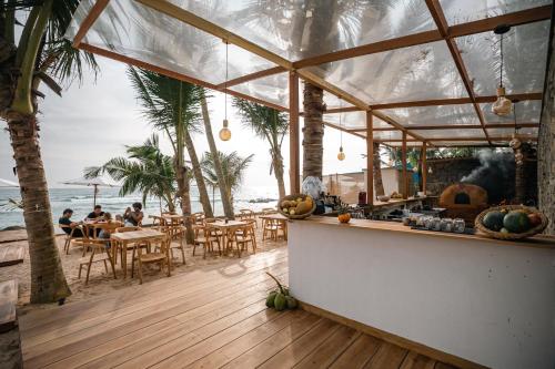 a restaurant on the beach with people sitting at tables at The Hotel in Ahangama