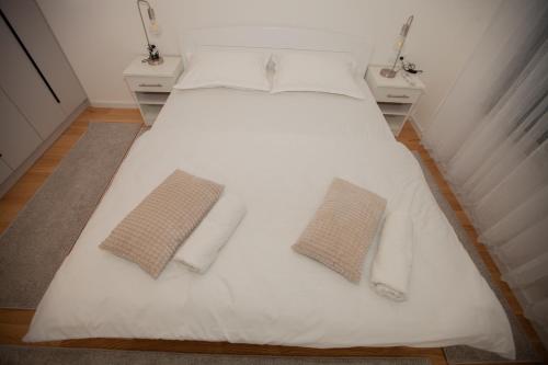 a large white bed with two pillows on it at Apartman Kuburica in Trebinje