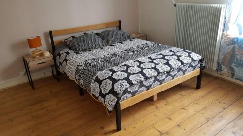 a bedroom with a bed with a black and white comforter at La Maison de Lucette in Fourmies