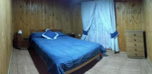 a bedroom with a blue bed and a window at Cabañas Anny in Linares