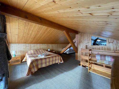 Cette chambre mansardée comprend un lit et un plafond en bois. dans l'établissement Hotel Le Very, aux Saisies