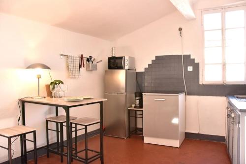 une cuisine avec un réfrigérateur et une table avec des tabourets dans l'établissement Lovely flat in the heart of the medieval city, à Hyères