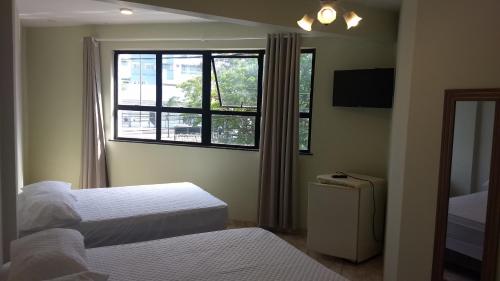 sypialnia z 2 łóżkami i oknem w obiekcie Suítes Cabo Frio w mieście Cabo Frio