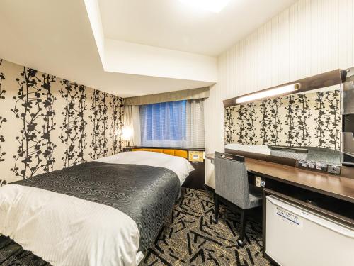 新潟市にあるアパホテル＆リゾート〈新潟駅前大通〉のベッドとデスクが備わるホテルルームです。