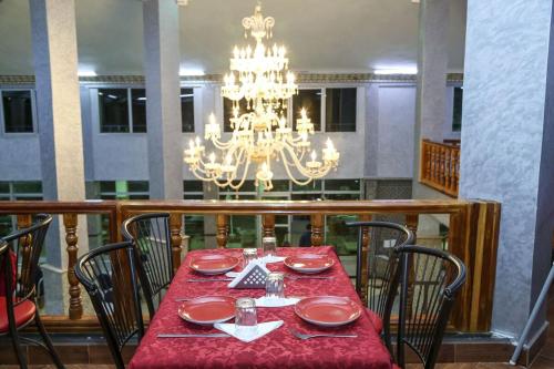comedor con mesa roja y lámpara de araña en HOTEL LA POMME ZAIDA en Zaida