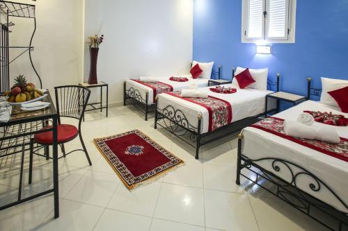 a room with three beds and a table and chairs at HOTEL LA POMME ZAIDA in Zaida