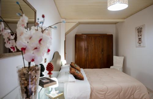 a bedroom with a bed and a vase with flowers at La Grua House in Castelbuono