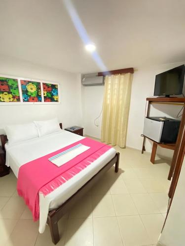 a bedroom with a bed and a flat screen tv at Hotel La Guajira in Ríohacha