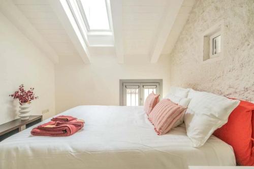 a bedroom with a white bed with pink and white pillows at [Penthouse] Piazza San Giacomo in Udine