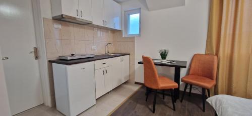 a kitchen with a sink and a table with chairs at Apartmani Ostojic in Vrdnik