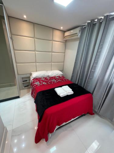 ein Schlafzimmer mit einem roten Bett mit Handtüchern darauf in der Unterkunft Apartamento loft 103 in Balneário Camboriú