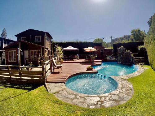 a swimming pool with a wooden deck next to a house at CABAÑAS AIRES DE MAROMILLAS in Constitución