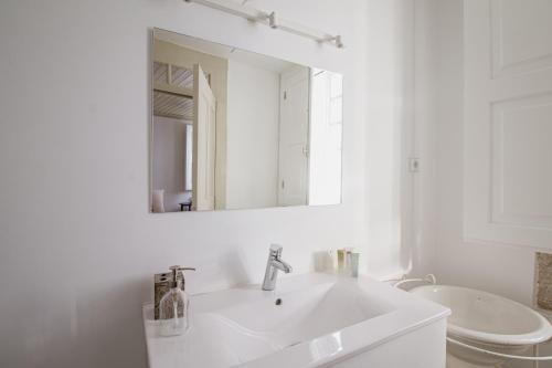 Baño blanco con lavabo y espejo en Casa da Judiaria Velha, en Viseu