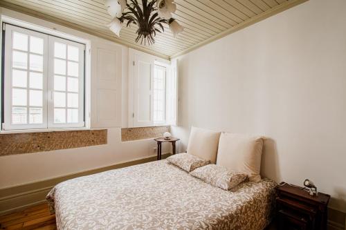 a bedroom with a bed and two windows at Casa da Judiaria Velha in Viseu