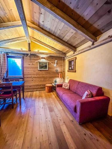 ein Wohnzimmer mit einem lila Sofa und einem Tisch in der Unterkunft La Buca delle Fate in Gressan