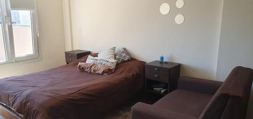 1 dormitorio con 1 cama con 2 almohadas y 1 silla en Mono Villegas 1 en San Carlos de Bariloche