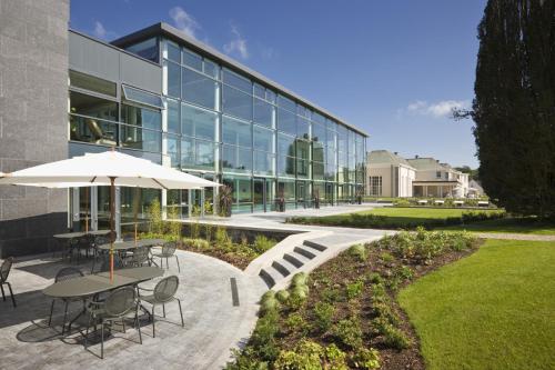 a building with tables and an umbrella in front of it at Castlemartyr Resort Hotel in Castlemartyr