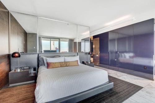 One Bedroom Suite with Strip Views 22nd Floor. في لاس فيغاس: غرفة نوم بسرير ابيض كبير وجدران زجاجية