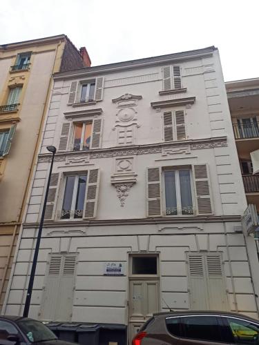 um edifício branco com janelas e portas numa rua em Joffre thermes em Vichy