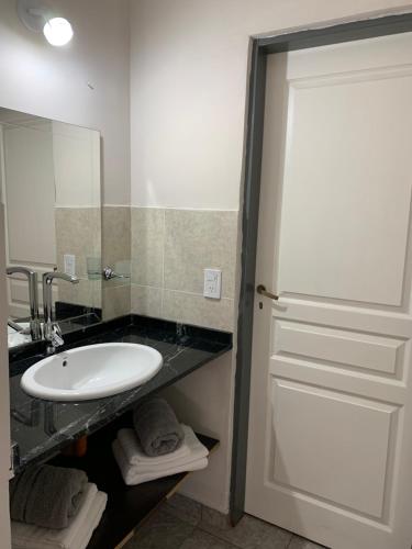 a bathroom with a sink and a white door at Casa de Ali in Villa Carlos Paz