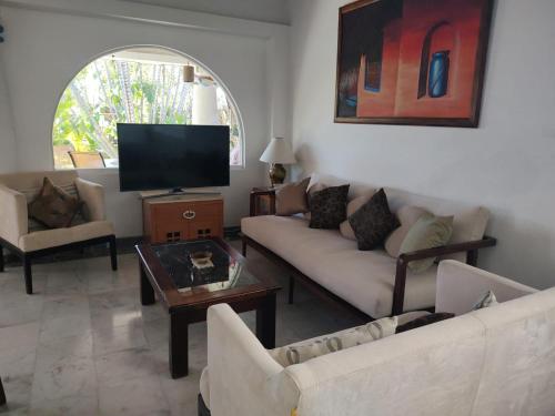 a living room with a couch and a tv at Aventura Pacifico Boutique Hotel in Bucerías