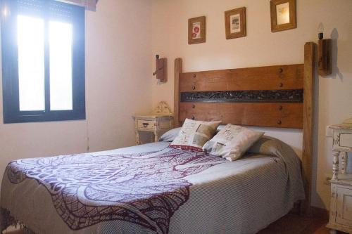 een slaapkamer met een groot bed met een houten hoofdeinde bij CASA HUGANA in Benalup Casas Viejas