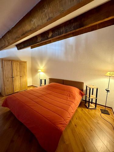 - une chambre avec un grand lit et un couvre-lit orange dans l'établissement LE MONTAGNARD, à Isola 2000