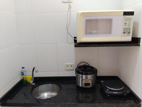 a kitchen counter with a sink and a microwave at Boa Vida Ubatuba in Ubatuba