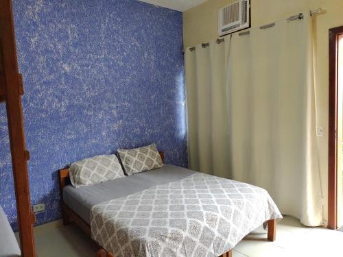 1 dormitorio con cama y pared azul en Boa Vida Ubatuba, en Ubatuba