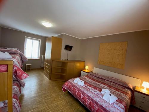a hotel room with two beds and a dresser at Soggiorno Dolomiti in Mazzin