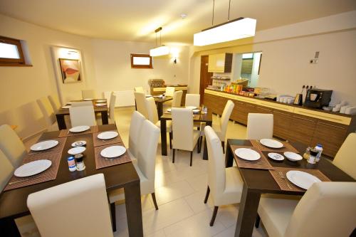 a dining room with wooden tables and white chairs at Airport Wellness Panzio in Hajdúszoboszló