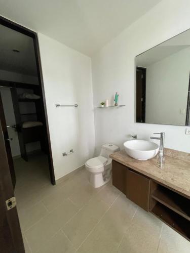 y baño con lavabo, aseo y espejo. en Acogedor apartamento con vista al mar en coveñas, en Coveñas