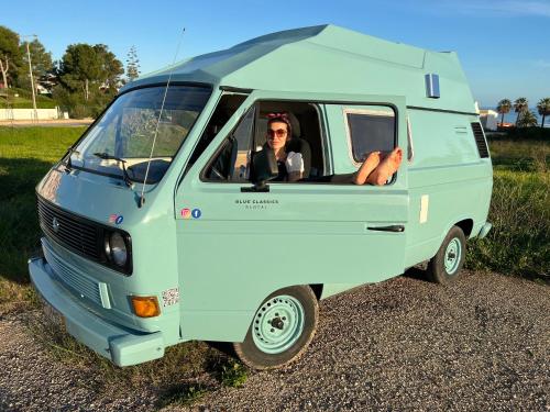 a woman sitting in the back of a blue van at Rent a BlueClassics 's campervan vw T3 azulina in Algarve au Portugal, in Portimão
