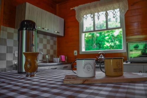 two coffee mugs sitting on a table in a kitchen at Refúgio das Uvas * Casa do Lago in Frederico Westphalen