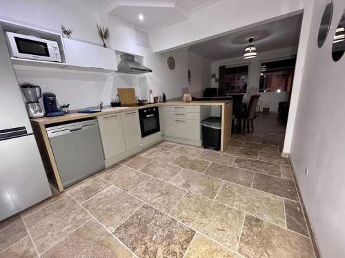 une cuisine avec des armoires blanches et un sol carrelé dans l'établissement Maison plein cœur de Rosendael, à Dunkerque