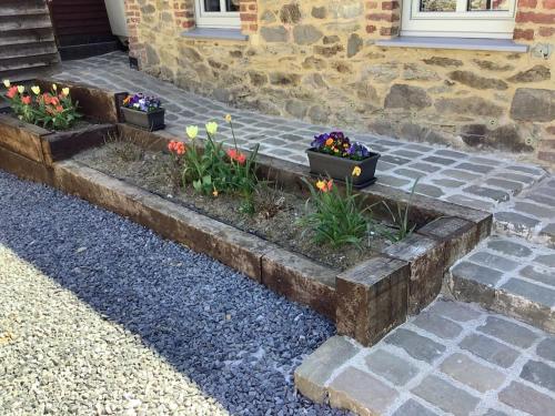 three flower boxes on a brick walkway with flowers at La Maisonnette in Porcheresse