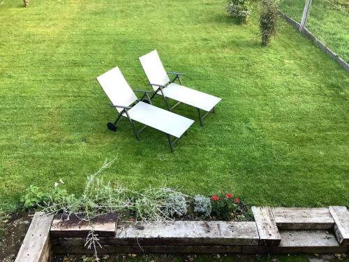 two white chairs and a table in a yard at La Maisonnette in Porcheresse