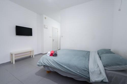 Schlafzimmer mit einem Bett und einem Flachbild-TV in der Unterkunft Luxury studio 5 min from beach in Rischon LeZion