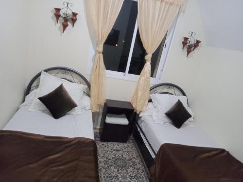 two beds in a room with a window at Dar yassmine in Ifrane