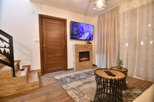 a living room with a fireplace and a tv on the wall at Brvnara Mont in Zlatibor