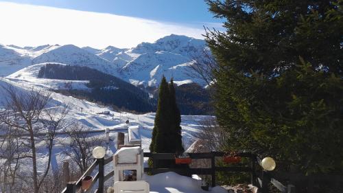 a view of a snow covered mountain with a tree at Casa Lory in Prato Nevoso