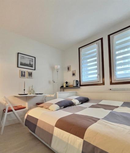 a bedroom with a bed and a desk and two windows at Studio confort Vanves Paris Porte de Versailles in Vanves