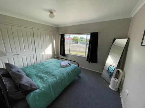 a bedroom with a green bed and a mirror at Comfortable 2-Bedroom home in Mudgee - Rest Easy Mudgee in Mudgee