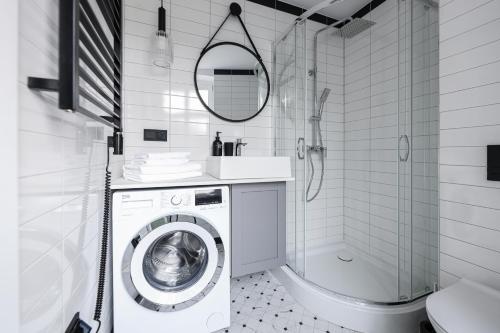 a white bathroom with a washing machine and a shower at Sea Zone Apartament przy parku in Wejherowo