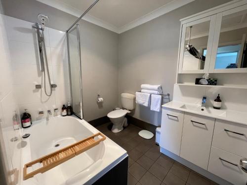 a bathroom with a tub and a sink and a toilet at Comfortable 2-Bedroom home in Mudgee - Rest Easy Mudgee in Mudgee