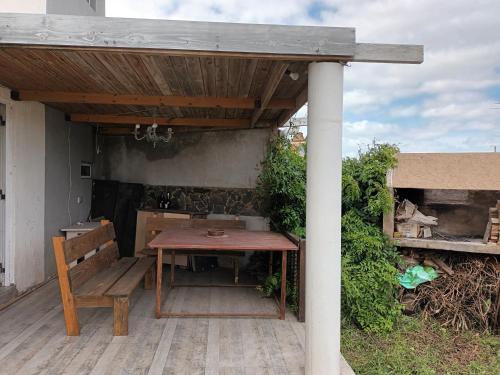 a wooden table and bench under a wooden roof at Playa Dorada, fte mar, gran 2 amb 4 pax, quincho parrilla in Santa Clara del Mar