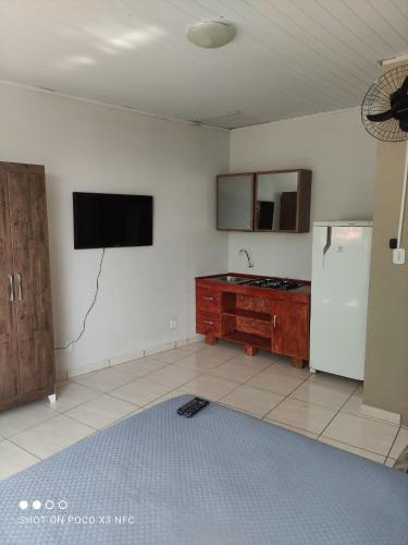 a kitchen with a refrigerator and a tv on the wall at Loft's Rio in Aracaju