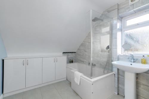 een witte badkamer met een wastafel, een bad en een toilet bij Cadwell Serviced 4 Bedroom House with Parking Maidenhead by 360Stays in Maidenhead